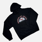 The "Bushcraft Sucks | Hoodie" by Überleben is a classic-fit black hooded sweatshirt, featuring a brushed interior and a front pocket. It displays a graphic of a cartoon style man walking through a bush encircled by text reading "BUSHCRAFT SUCKS" in red and white letters. 