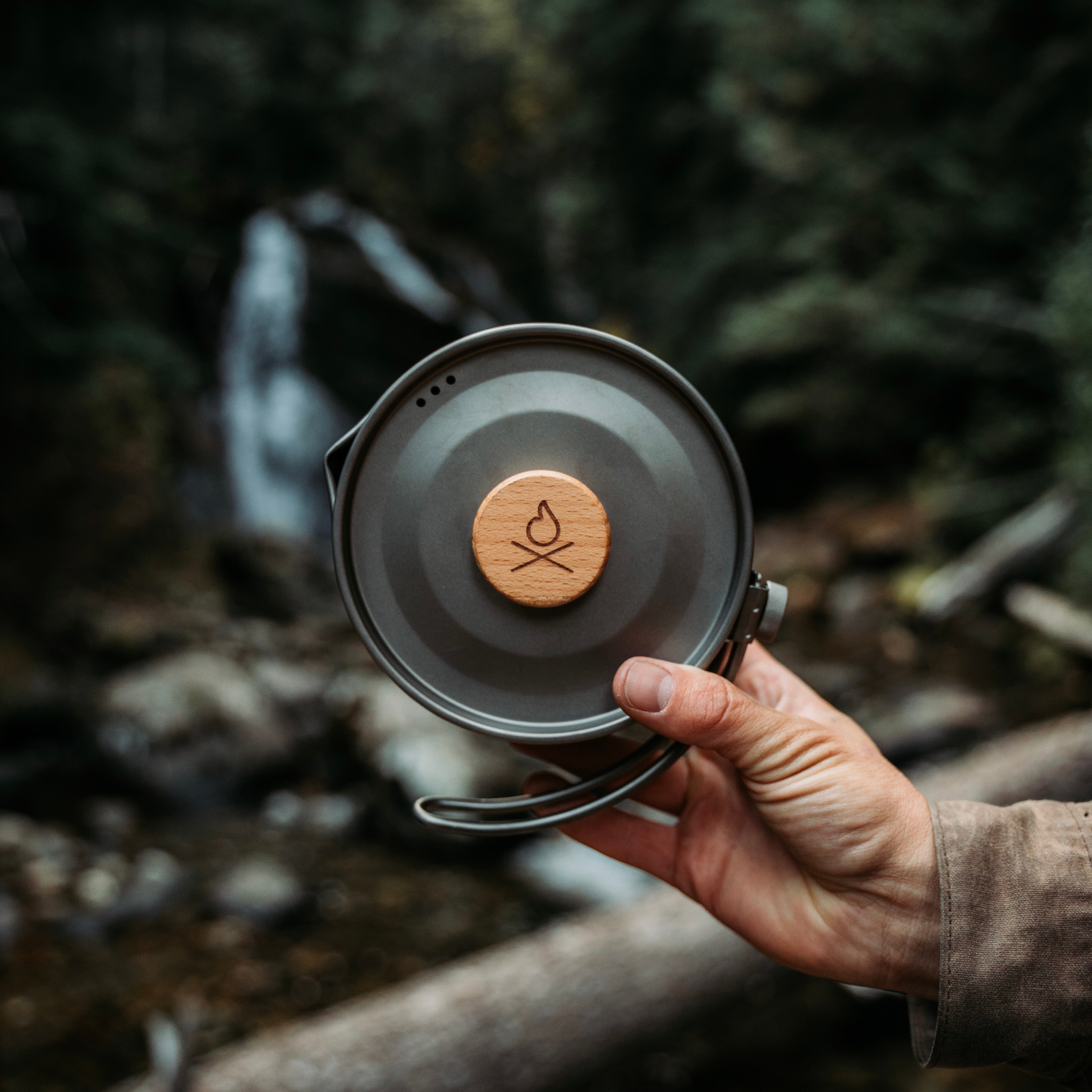 Hand holding up an Überleben lightweight backpacking Titanium Kessel Pot.